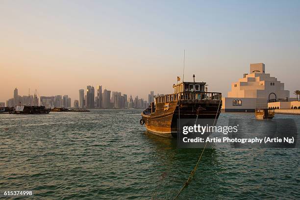 view of doha skyline along doha bay with traditional dhow in the foreground and museum of islamic art on the right, doha, qatar - dhow qatar stock pictures, royalty-free photos & images