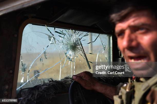 Kurdish Peshmerga fighter leans out of his military vehicle which has taken several direct hits from ISIS snipers including on the windscreen on...