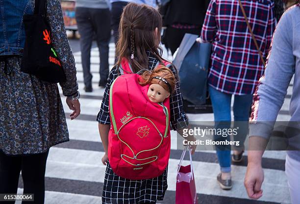 Girl carries an American Girl doll in a backpack while walking along 5th Avenue in New York, U.S., on Monday, Oct. 17, 2016. Mattel Inc., the parent...