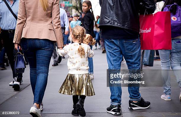 Girl carries an American Girl doll while walking along 5th Avenue in New York, U.S., on Monday, Oct. 17, 2016. Mattel Inc., the parent company of...