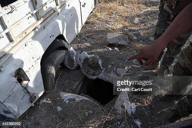 Kurdish Peshmerga soldier gestures towards a tunnel dug by ISIS fighters in a village recently recaptured by the Kurds during the battle to retake...