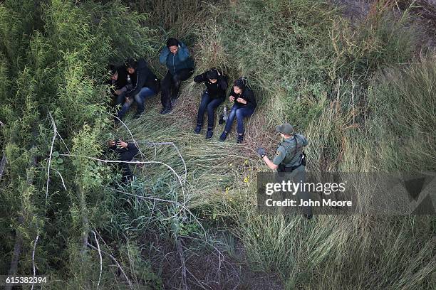 Border Patrol agent detains a group of undocumented immigrants on October 18, 2016 near McAllen, Texas. Border Patrol agents coordinate with U.S. Air...