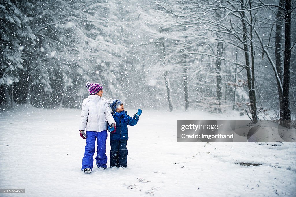 Brother and sister walking in snowy forest