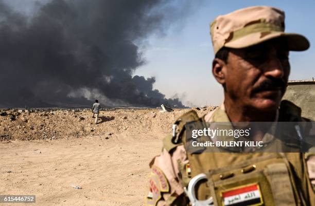 Member of Iraqi forces stands as smoke billows from the town of Qayyarah, south of Mosul, during the operation to recapture the city from the Islamic...
