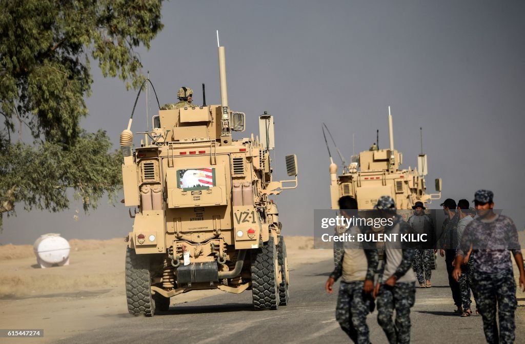 Members of Iraqi forces walk near a MRAP armoured vehicle used by US ...