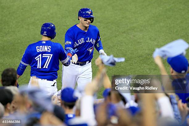 Troy Tulowitzki of the Toronto Blue Jays celebrates with teammate Ryan Goins after scoring a run off of a single to center field hit by Ezequiel...