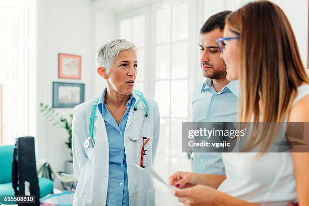 pareja joven con el médico en una consulta - infertilidad fotografías e imágenes de stock