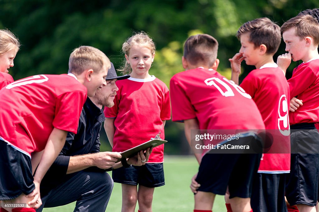 Childrens soccer coach talking to his co-ed team
