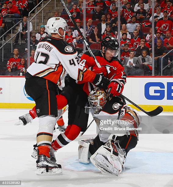 Josh Manson of the Anaheim Ducks checks Adam Henrique of the New Jersey Devils into John Gibson during the second period at the Prudential Center on...