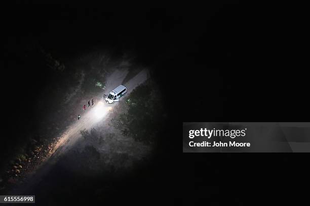 Spotlight from a U.S. Customs and Border Protection helicopter shines women and children seeking asylum on October 18, 2016 in McAllen, Texas. U.S....