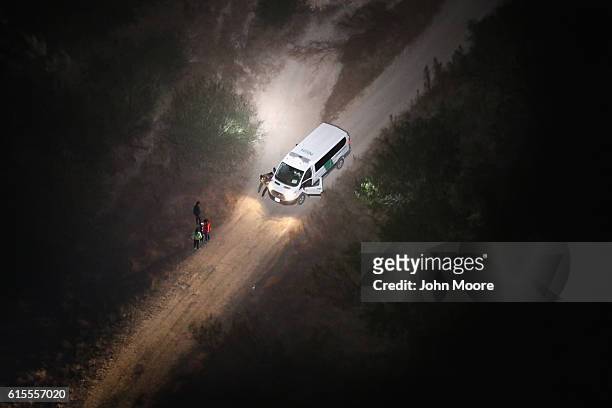 Spotlight from a U.S. Customs and Border Protection helicopter shines on women and children seeking asylum on October 18, 2016 in McAllen, Texas....