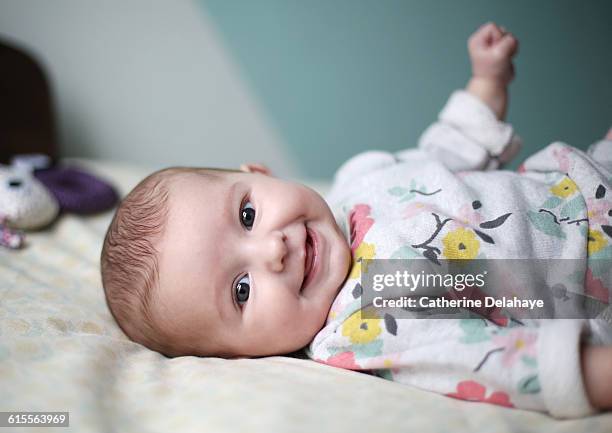 a baby girl smiling on a bed - weibliches baby stock-fotos und bilder