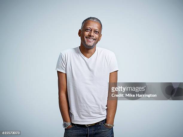 mature male smiling with hands in pockets - studioaufnahme stock-fotos und bilder