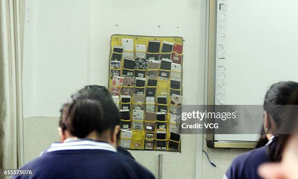 Bag storing students' mobile phones hangs next to the blackboard in a classroom of a vocational and technical school at Tonglu County on October 19,...