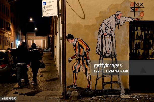 Picture of a new street art mural by Italian artist Maupal showing Pope Francis playing tic-tac-toe and drawing peace signs as a Swiss guard keep...