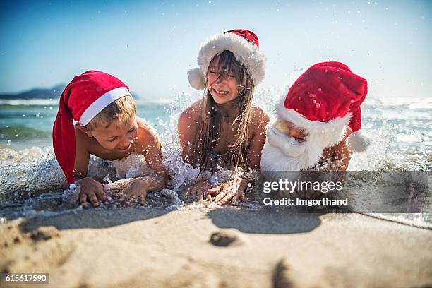 kids having fun on the beach during christmas - santa claus lying stockfoto's en -beelden