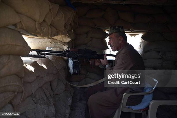 Kurdish peshmerga soldier holds his machine gun toward a road to Mosul as forces continue the battle to retake Mosul, on October 19, 2016 in Bashiqa,...