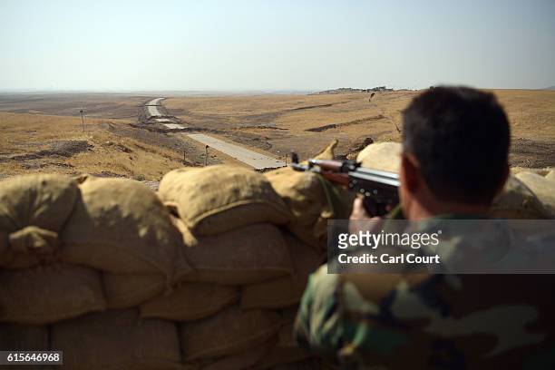 Kurdish peshmerga soldier aims his rifle toward a road to Mosul as forces continue the battle to retake Mosul, on October 19, 2016 in Bashiqa, near...