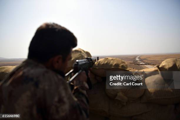 Kurdish peshmerga soldier aims his rifle toward a road to Mosul as forces continue the battle to retake Mosul, on October 19, 2016 in Bashiqa, near...