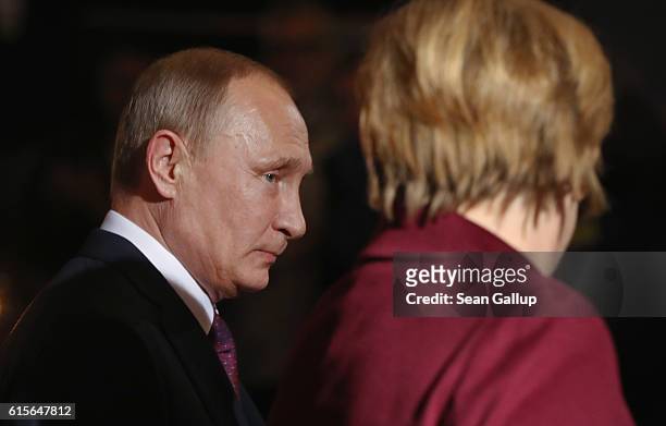 Russian President Vladimir Putin walks with German Chancellor Angela Merkel upon his arrival to discuss the Ukrainian peace process at the...
