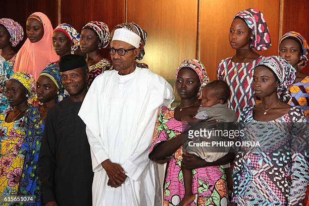 Nigerian President Muhammadu Buhari poses on October 19, 2016 with the 21 Chibok girls who were released by Boko Haram last week, at the State House...