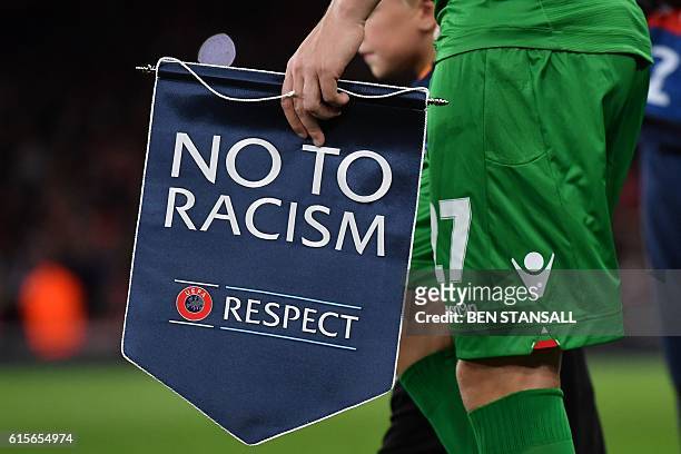 Ludogorets' Romanian defender Cosmin Moti holds an anti-racism banner ahead of the UEFA Champions League Group A football match between Arsenal and...