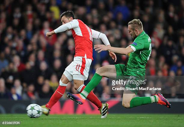 Mesut Ozil breaks past Ludogorets defender Cosmin Moti to score the 4th Arsenal goal during the UEFA Champions League match between Arsenal FC and...