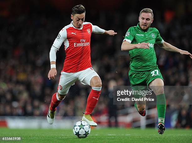 Mesut Ozil scores Arsenal's 4th goal under pressure from Cosmin Moti of Ludogorets during the UEFA Champions League match between Arsenal FC and PFC...