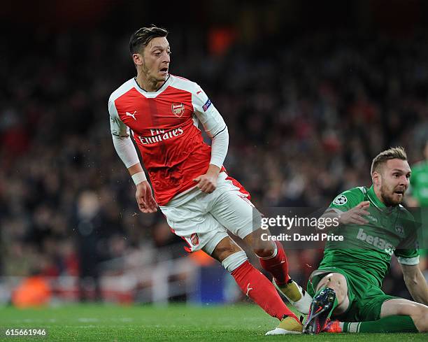 Mesut Ozil scores Arsenal's 4th goal under pressure from Cosmin Moti of Ludogorets during the UEFA Champions League match between Arsenal FC and PFC...