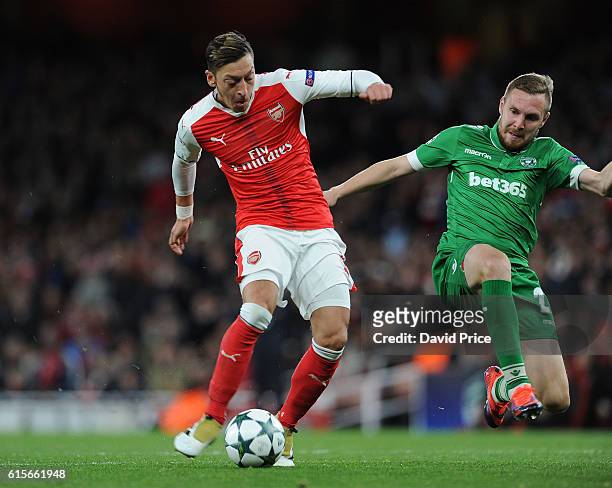 Mesut Ozil scores Arsenal's 4th goal under pressure from Cosmin Moti of Ludogorets during the UEFA Champions League match between Arsenal FC and PFC...