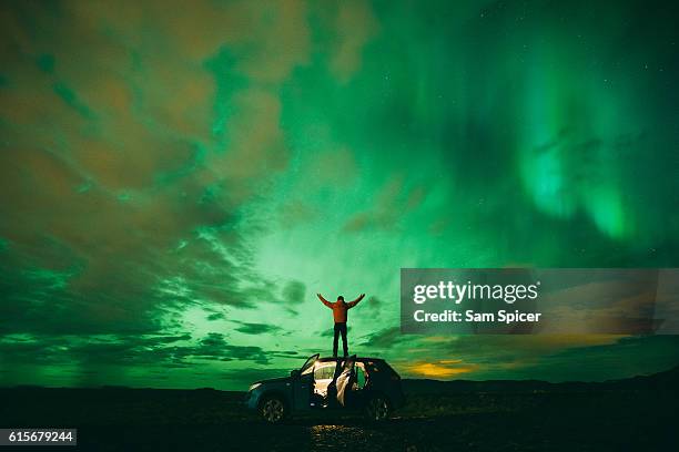 tourist enjoying the northern lights or aurora borealis in iceland - northern lights iceland stockfoto's en -beelden