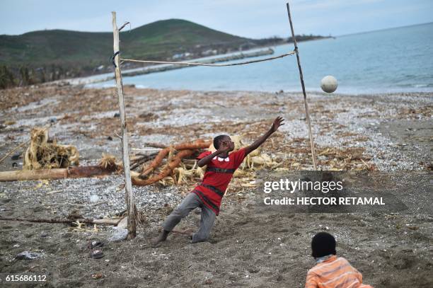Children play fooball on a damaged beach on October 19, 2016 in the aftermath of Hurricane Matthew in the commune of Port-a-Piment, southwestern...