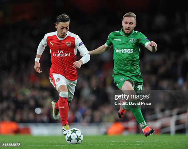 Mesut Ozil on his way to scoring Arsenal's 4th goal under pressure from Cosmin Moti of Ludogorets during the UEFA Champions League match between...