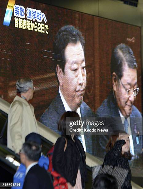 Japan - Passengers at Hankyu Umeda Station in Osaka glance at television news on Prime Minister Yoshihiko Noda's dissolution of the House of...