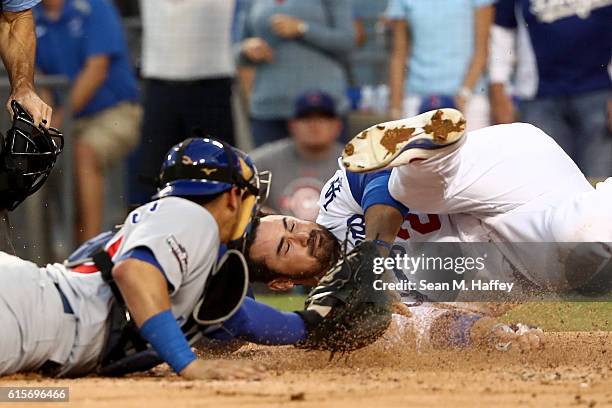 Adrian Gonzalez of the Los Angeles Dodgers slides into home as he attempts to get his left hand under the glove of catcher Willson Contreras of the...