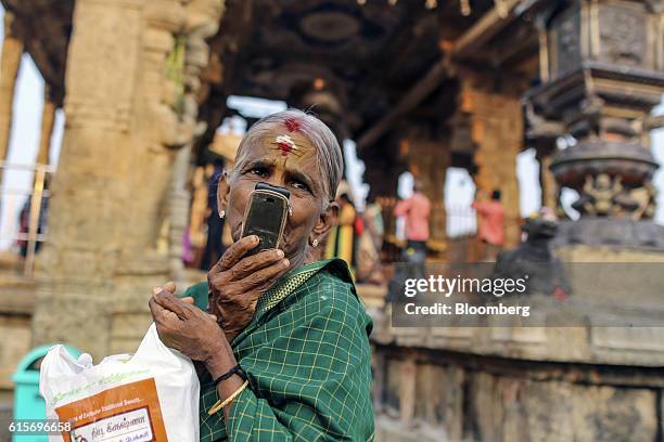 Devotee talks on mobile phone outside the Brihadeshwara Temple in Thanjavur, Tamil Nadu, India, on Sunday, Oct. 16, 2016. India's new central bank...