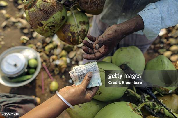 Customer hands an Indian one-hundred rupee banknote to a coconut vendor in Nagapattinam, Tamil Nadu, India, on Sunday, Oct. 16, 2016. India's new...