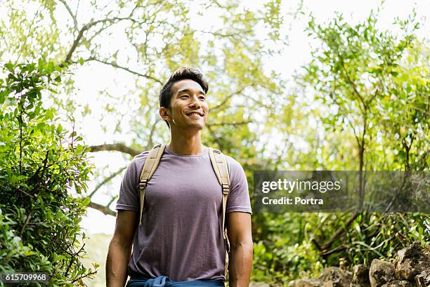 confident smiling hiker standing against trees - backpacker stock pictures, royalty-free photos & images