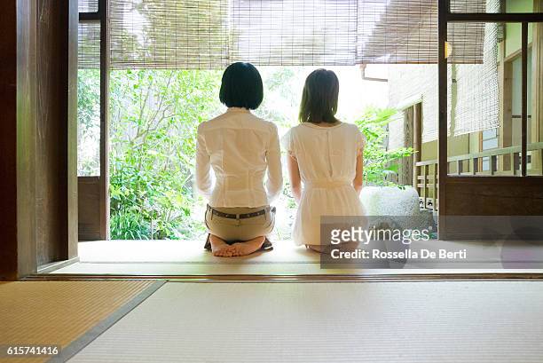 two japanese women contemplating the garden from the veranda - tatami mat stockfoto's en -beelden