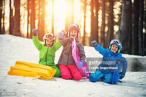 happy kids with toboggans enjoying winter - sports helmet stock pictures, royalty-free photos & images