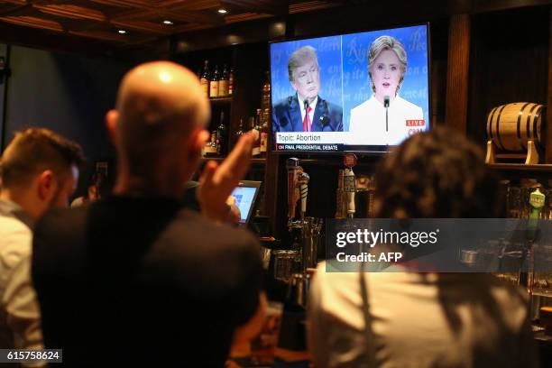 People watch the third presidential debate between presidential debate between US Democratic presidential candidate Hillary Clinton and US Republican...