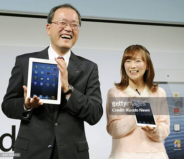 Japan - TV-personality Satomi Shigemori holds the iPad mini, while KDDI Corp. President Takashi Tanaka holds the new iPad 4 at KDDI's unveiling event...
