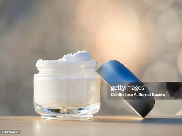 jar of moisturizing white cream opened,  illuminated with natural light - 乳液 ストックフォトと画像