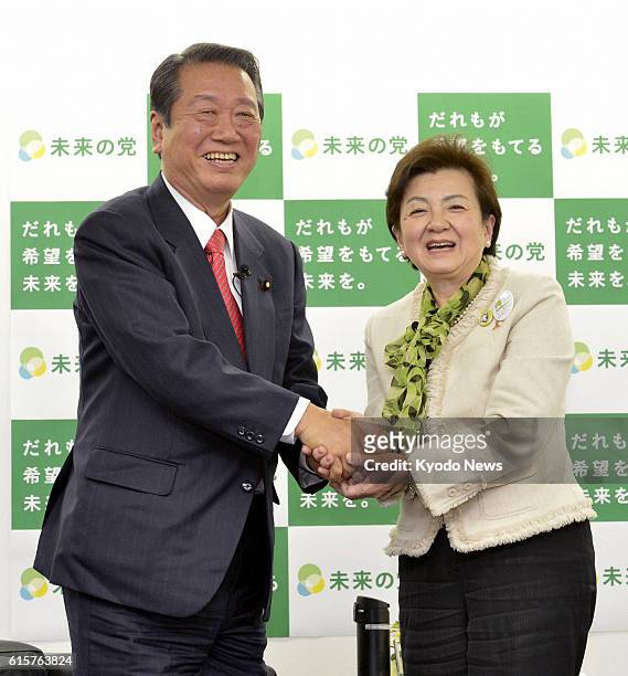 Japan - Shiga Gov. Yukiko Kada , leader of the Tomorrow Party of Japan, and Ichiro Ozawa, leader of the People's Life First party, shake hands after...