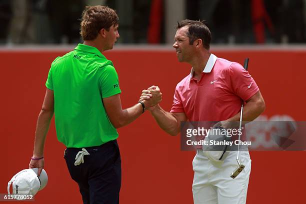 Paul Casey of England shakes hands with Kaufman Smylie of the United States on the 18th hole during day one of the 2016 CIMB Classic atthe TPC, Kuala...
