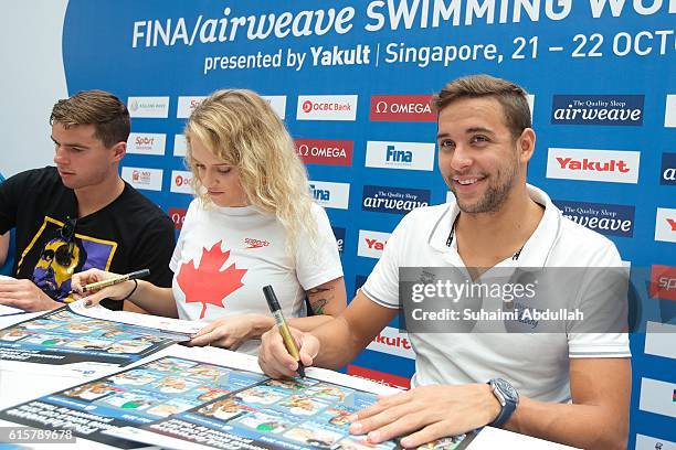 Josh Prenot of United States of America, Hilary Caldwell of Canada and Chad le Clos of South Africa sign autographs during the International Swim...