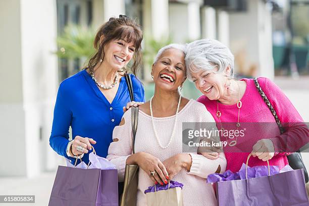 three multi-ethnic senior women out shopping - senior women shopping stock pictures, royalty-free photos & images