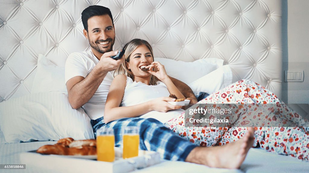 Couple watching tv in bedroom.