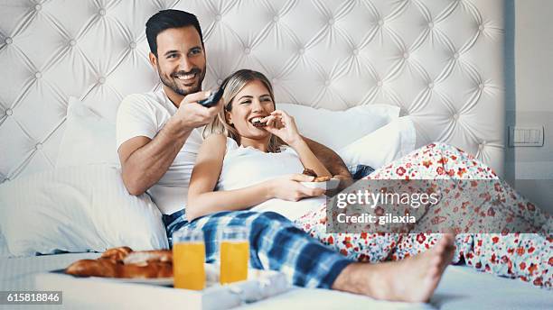 couple watching tv in bedroom. - confort at hotel bedroom stock pictures, royalty-free photos & images