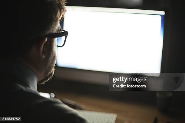 man looking at computer monitor - computer monitor back stock pictures, royalty-free photos & images